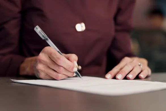 Person signing a paper document — document translation services by Loop Translate