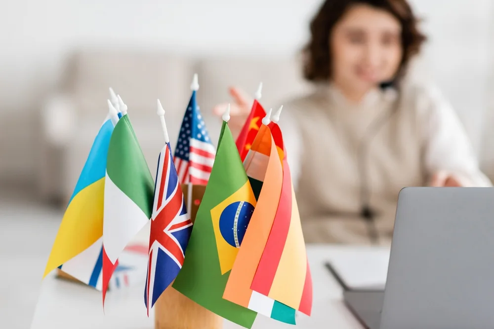 International desk flags beside a professional at a laptop — document translation services by Loop Translate