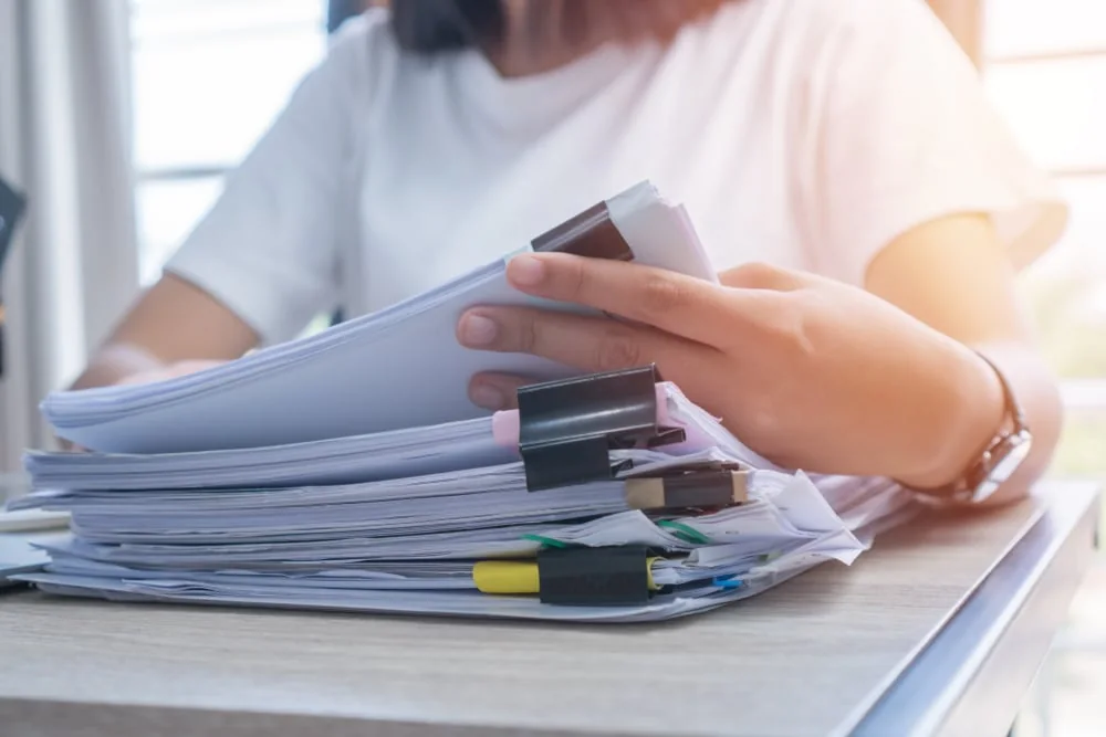 Professional checking a stack of paper records — document translation services by Loop Translate